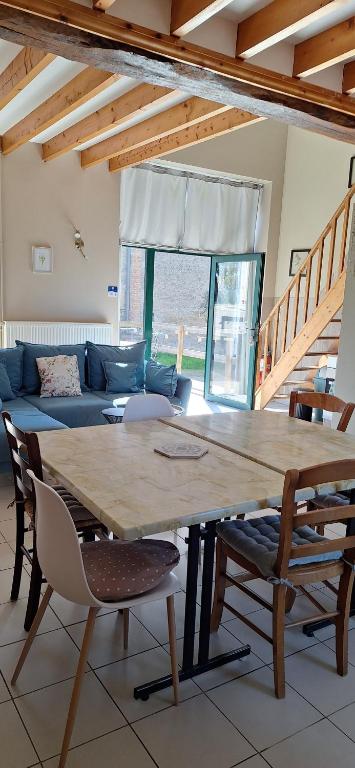 a large wooden table in a living room with a couch at La Maisonnette du Meslay in Fyé