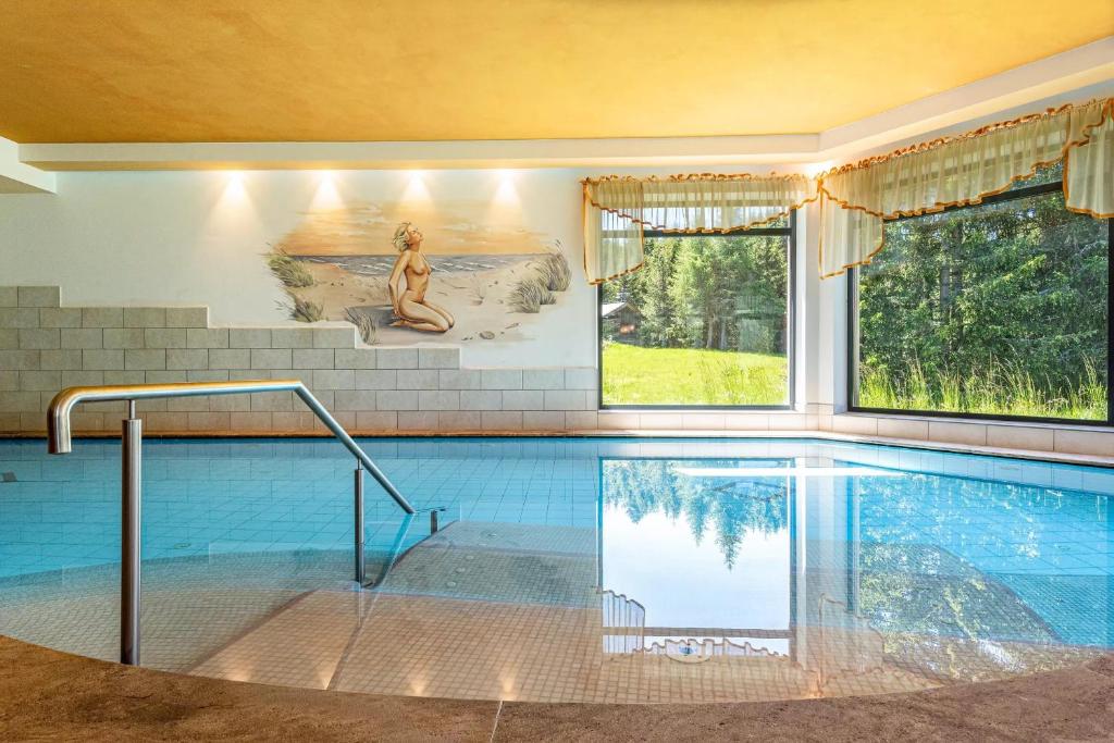 a swimming pool with a woman sitting on the side of it at Sabina Dolomites Spitzbühl in Alpe di Siusi