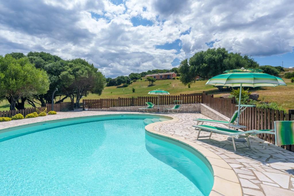 a swimming pool with a chair and an umbrella at Stella Marina Piscina e Vista Mare in Aglientu