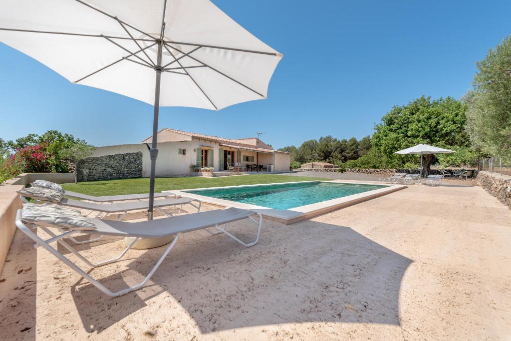 a chair with an umbrella next to a swimming pool at Finca Laurel in Islas Baleares