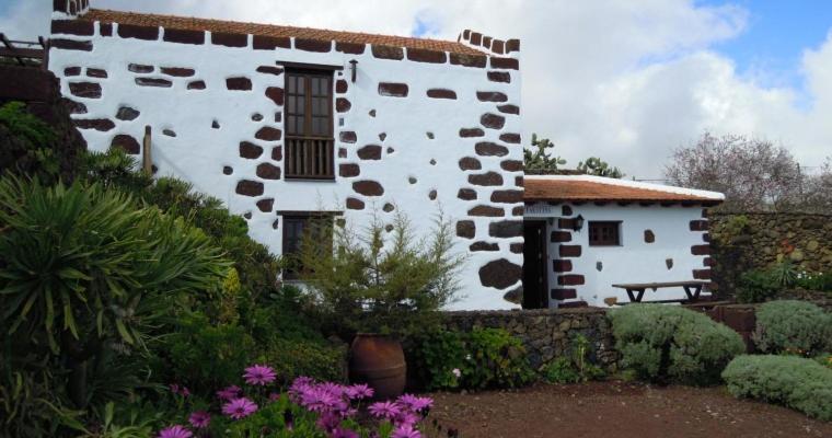 un edificio blanco con un banco en un jardín en Casa Rural Faustina, en Isora