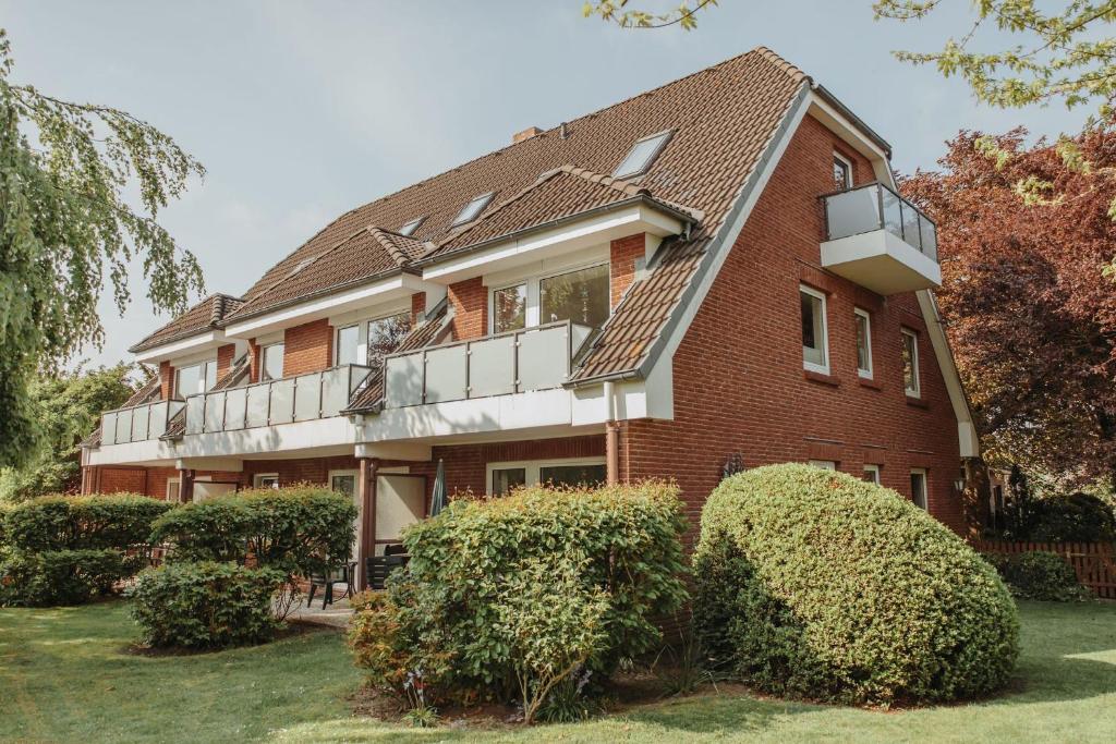a red brick house with bushes in front of it at Gästehaus Bröcker Wohnung 8 in Büsum