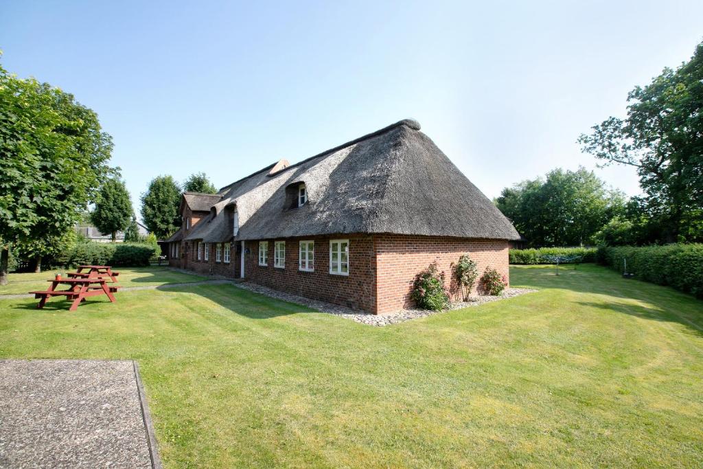 a building with a thatched roof with a picnic table at Friesisches Reetdachferienhaus in Bordelum