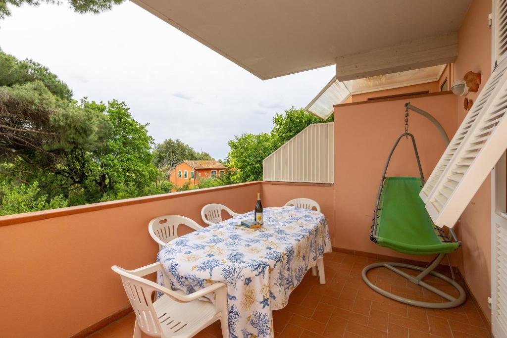 a balcony with a table and chairs and a green swing at Villetta a Castiglioncello in Castiglioncello