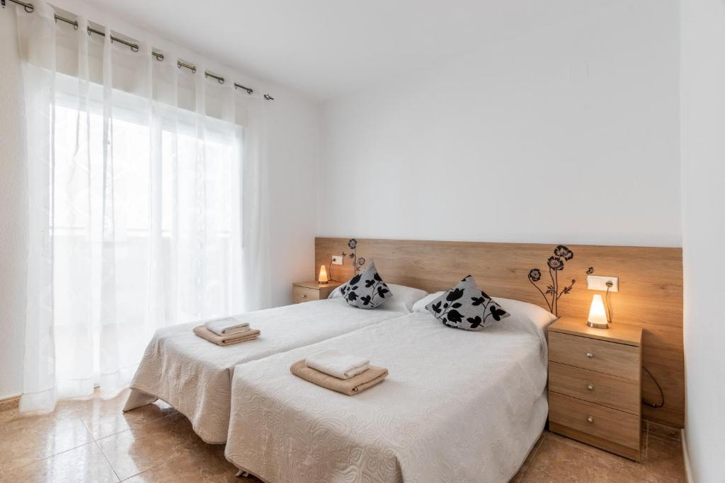 a white bedroom with a large bed with two pillows at Isabela in Calpe