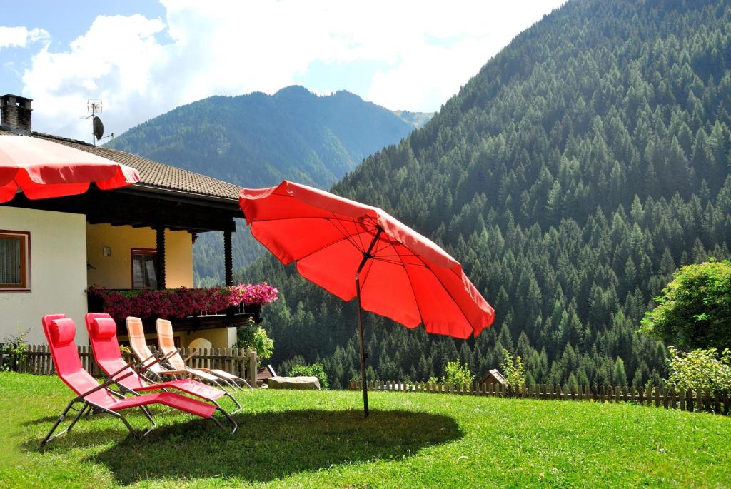 two chairs and a red umbrella in front of a house at Heiserhof App Kirsche in Racines
