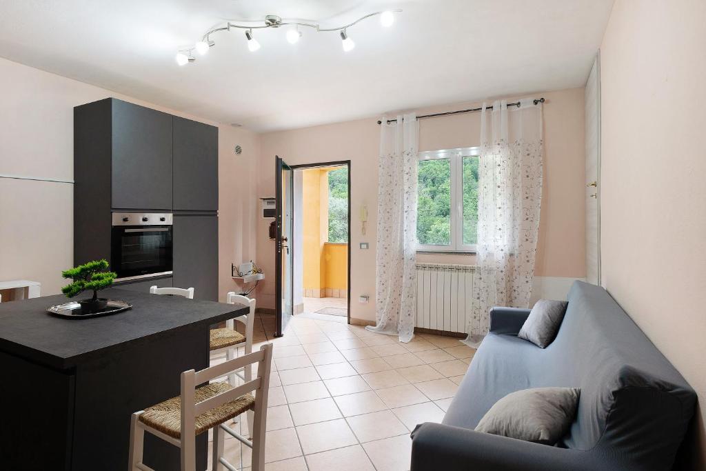 a living room with a blue couch and a kitchen at Il Frutteto 49 in Ortovero