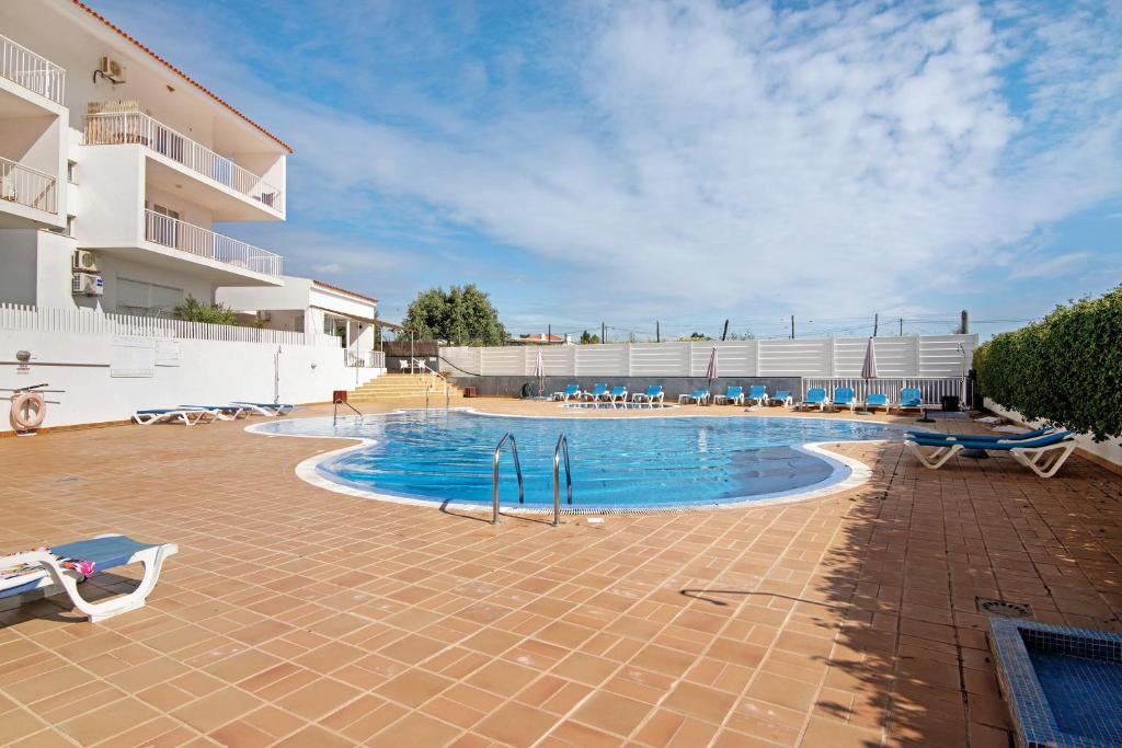 a large swimming pool with chairs and a building at Costa Cabanas 1 in Cabanas de Tavira