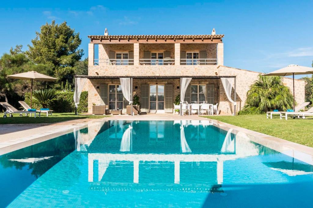 a villa with a swimming pool in front of a house at Can Bossa in Capdepera