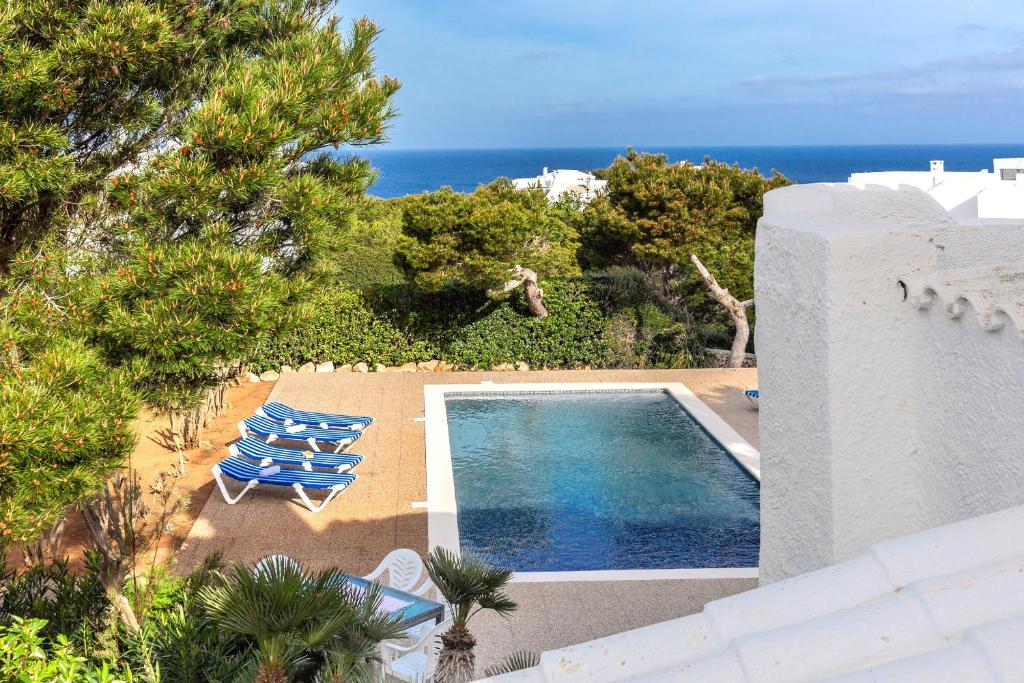 an image of a swimming pool with chairs and the ocean at Cavall Menor in Cala Morell