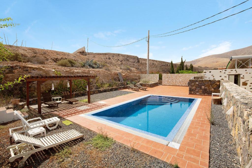 a swimming pool in a yard with two chairs at Casa del Valle in Betancuría