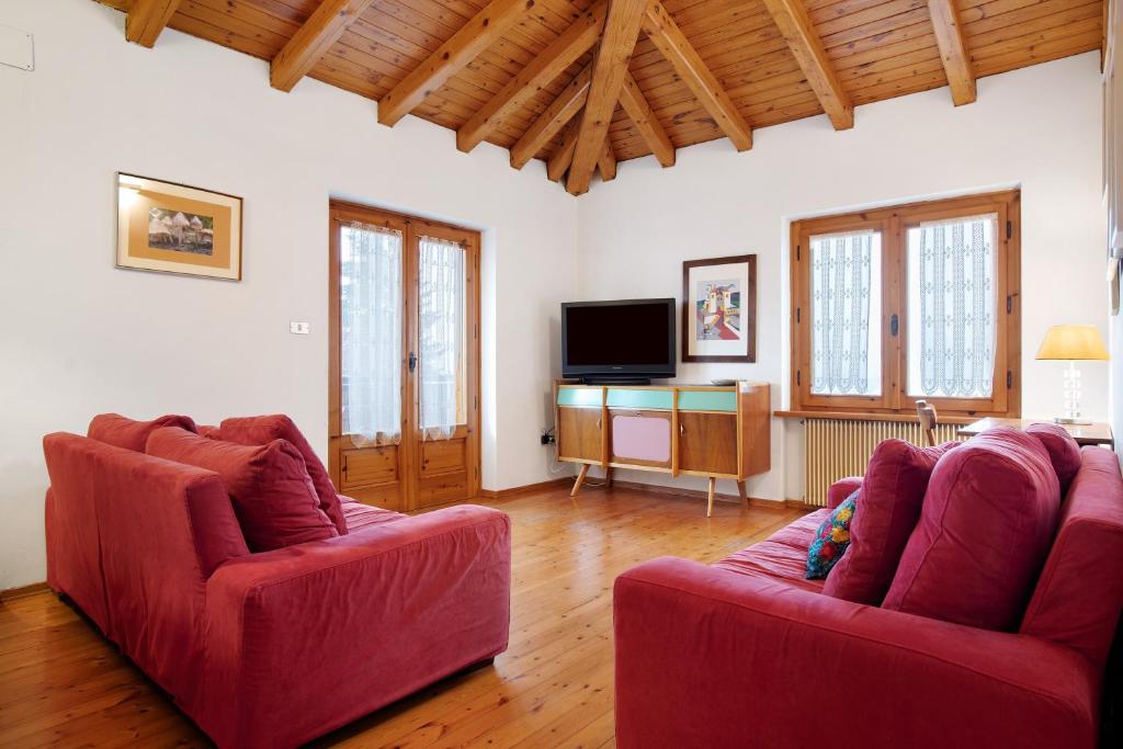 a living room with two red chairs and a tv at Casa Pòlse in Baselga di Pinè