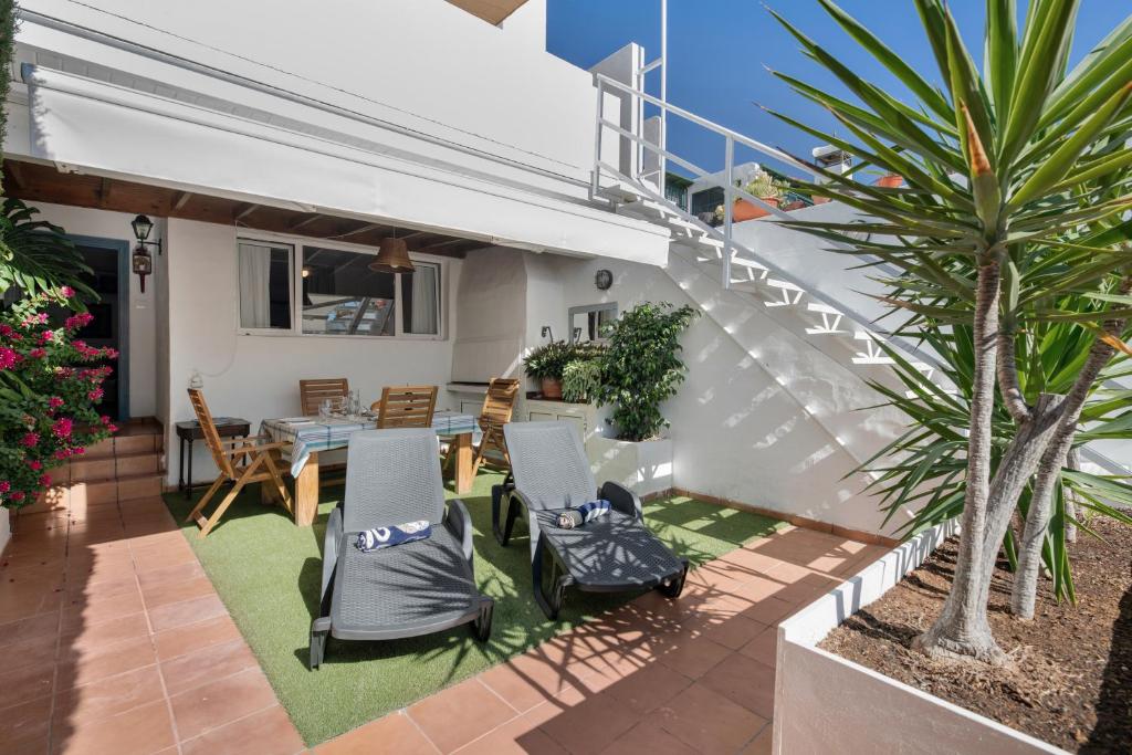 a patio with chairs and a table and a palm tree at Apartamento Cipreses in Puerto del Carmen