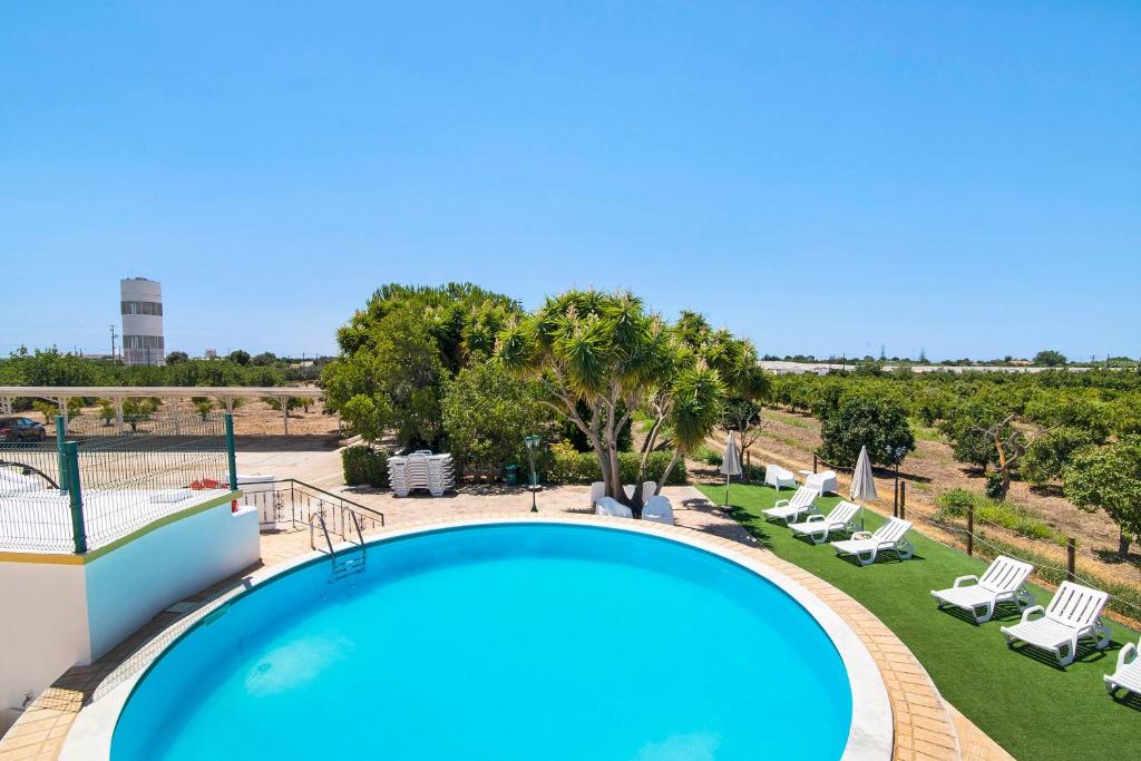 a large swimming pool with lounge chairs and trees at Quinta Alegre Tavira Moderno T2 in Luz de Tavira