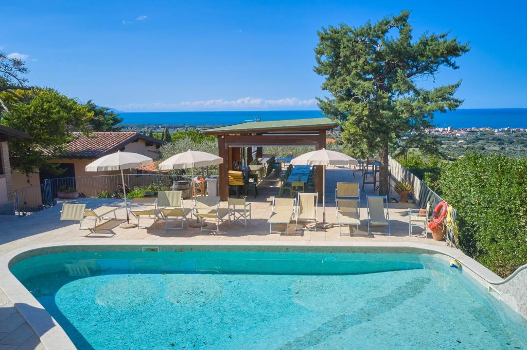 a swimming pool with chairs and tables and umbrellas at Blu - Euroappartamenti in San Vincenzo