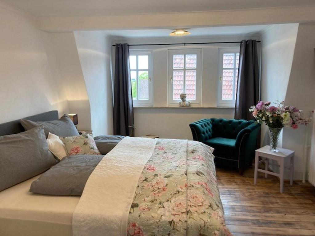 a bedroom with a bed and a chair and windows at Ferienwohnung Rahel in Münsingen
