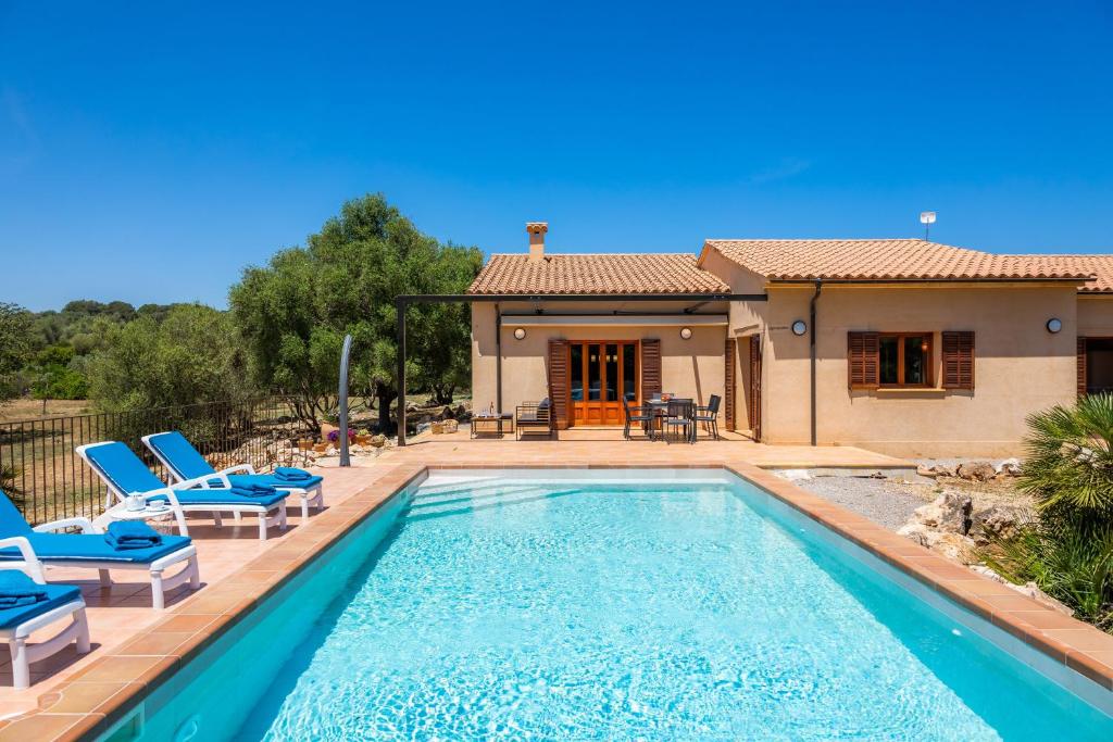 a swimming pool with chairs and a house at Finca Ca'n Terrasa in Capdepera