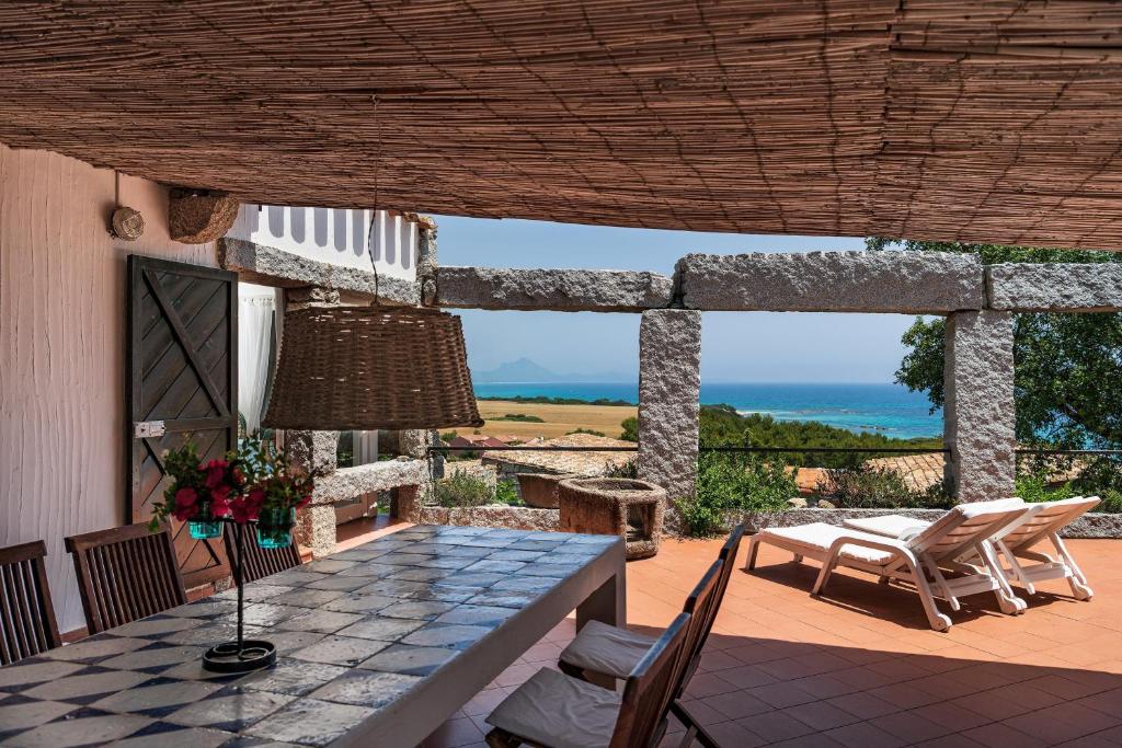 a table and chairs on a patio with a view of the ocean at Casa 23 in Castiadas
