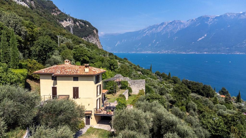 a house on a hill next to a body of water at Haus mit tollem See -und Bergblick in Gargnano