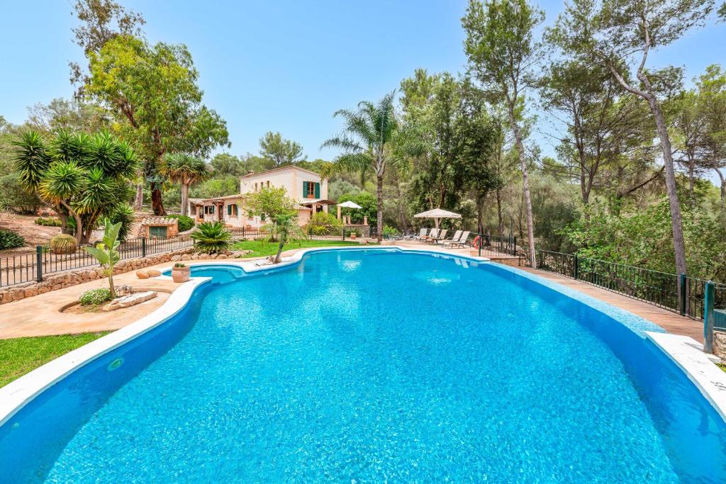 a swimming pool in front of a house with trees at Yuma in Llucmajor