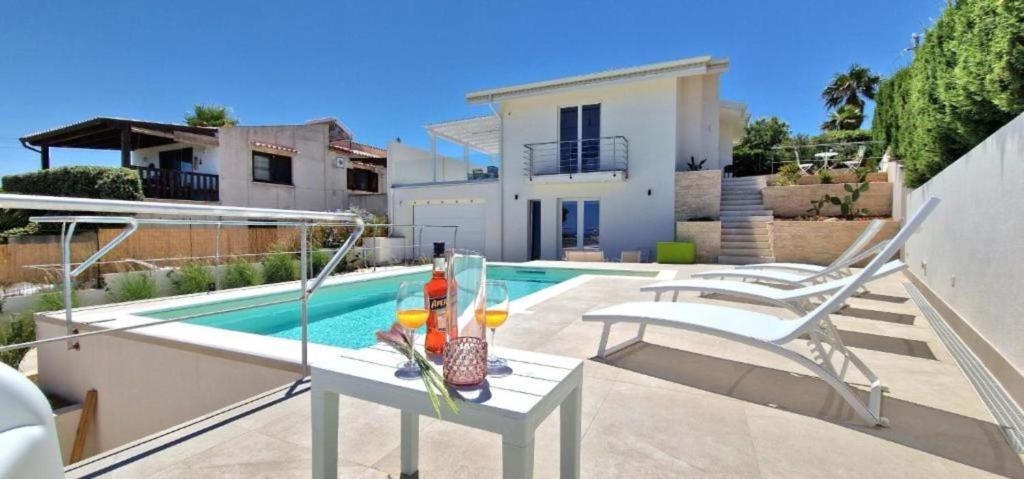 a patio with a table and chairs next to a pool at Villa Taliala in Alcamo Marina