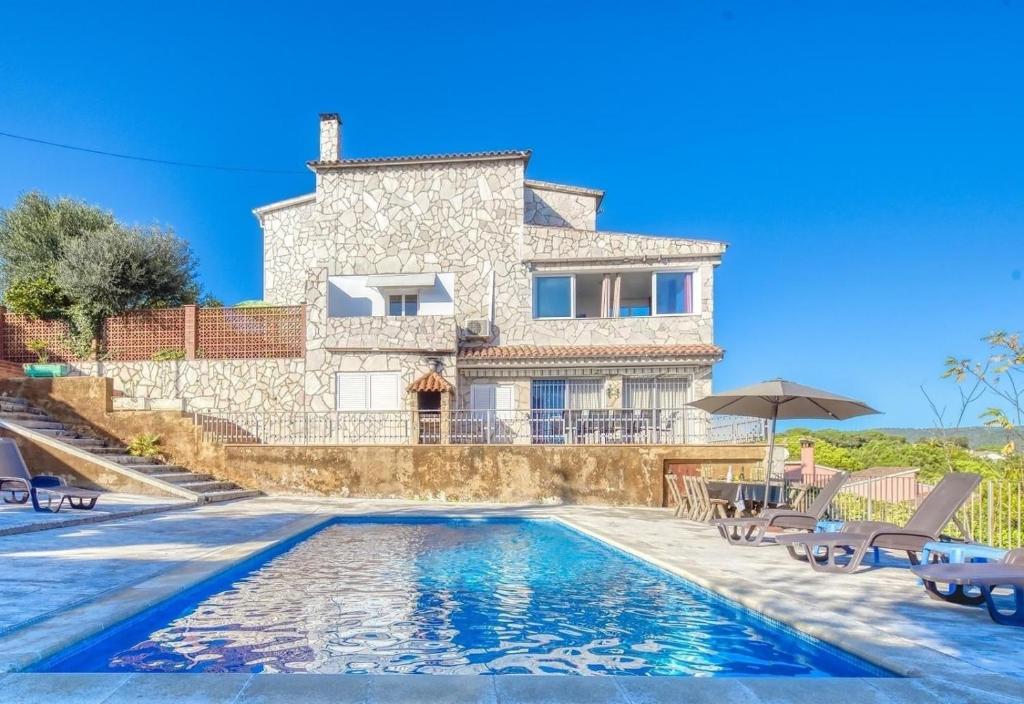 a villa with a swimming pool in front of a house at Costacabana - Villa Abigail in Lloret de Mar