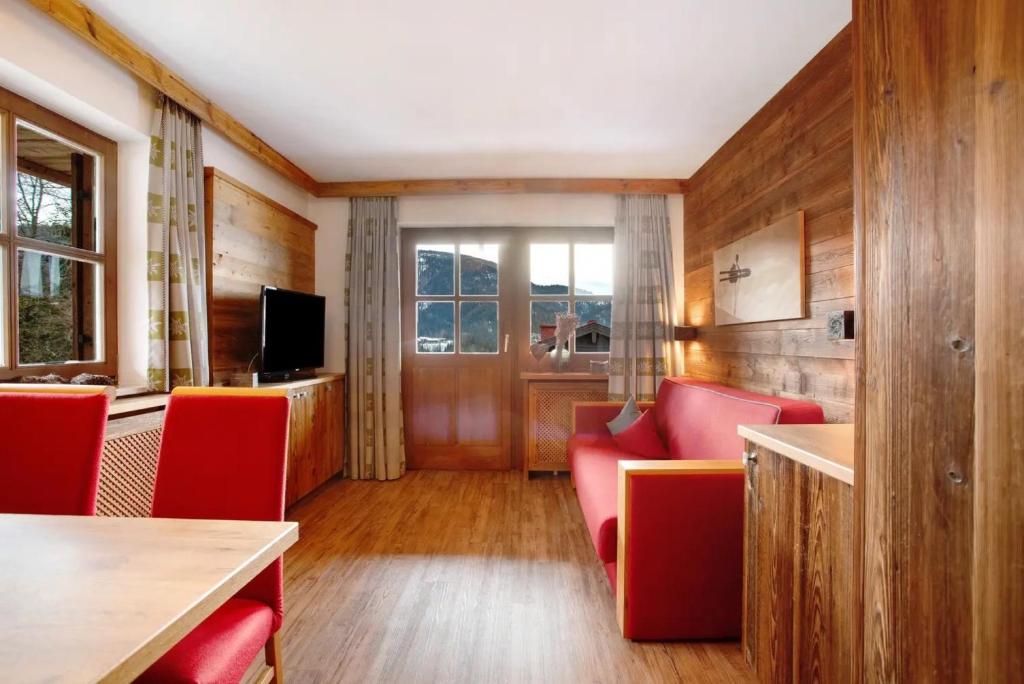 a living room with red chairs and a television at Gästehaus Panorama - Appartement 2 in Reit im Winkl