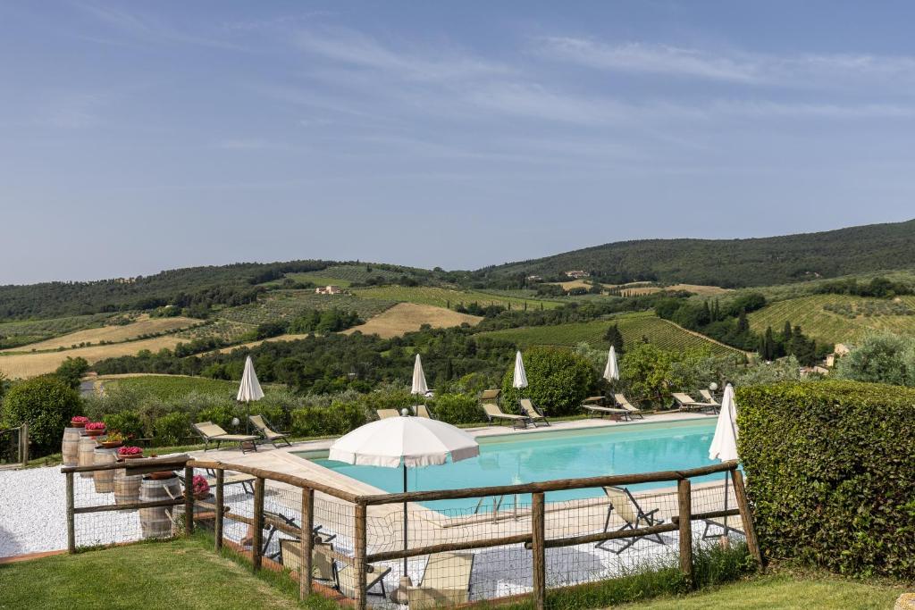 a pool with chairs and umbrellas and a view of a mountain at Suite Mezzatorre in San Gimignano