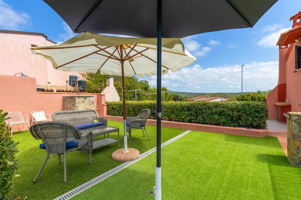 a patio with an umbrella and chairs on a lawn at Casa Erbì in Torre Dei Corsari