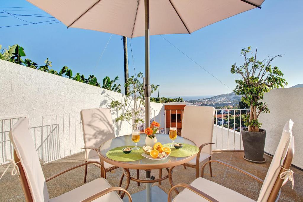 a table and chairs on a balcony with an umbrella at A Minha Casa in Funchal