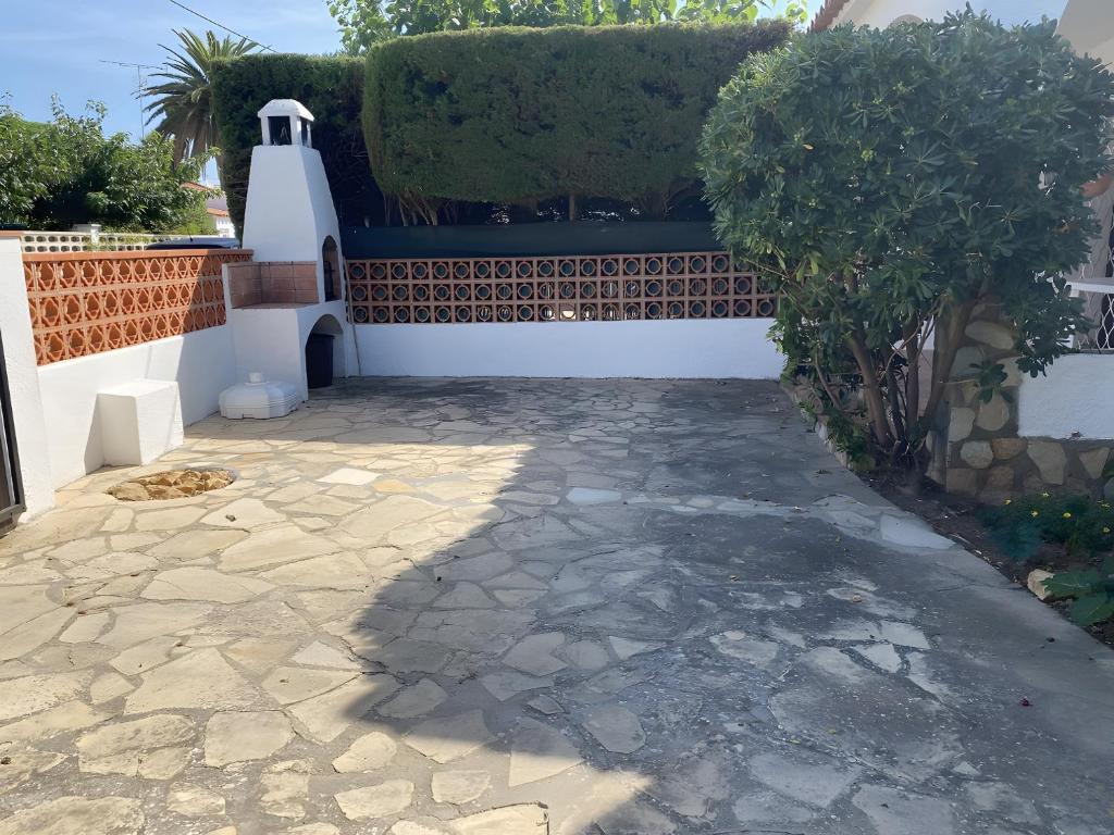 a patio with a white wall and a hedge at Villa Sylvie- Cerca Playa Riells- 4 in L'Escala