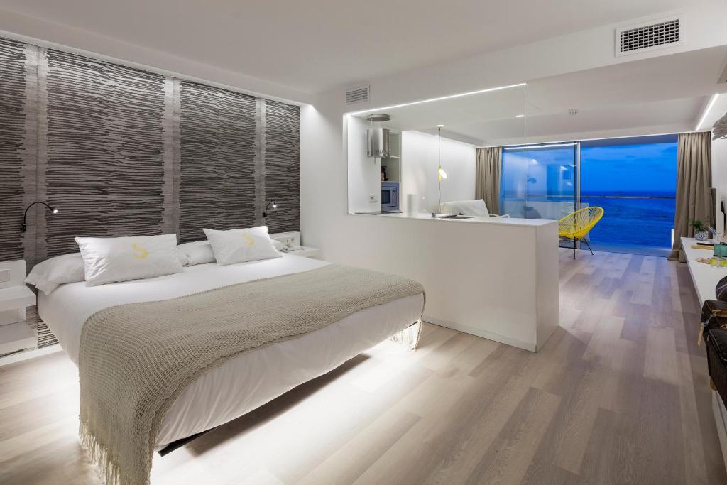 1 dormitorio con 1 cama y cocina con vistas. en Sud Ibiza Suites, en Ibiza