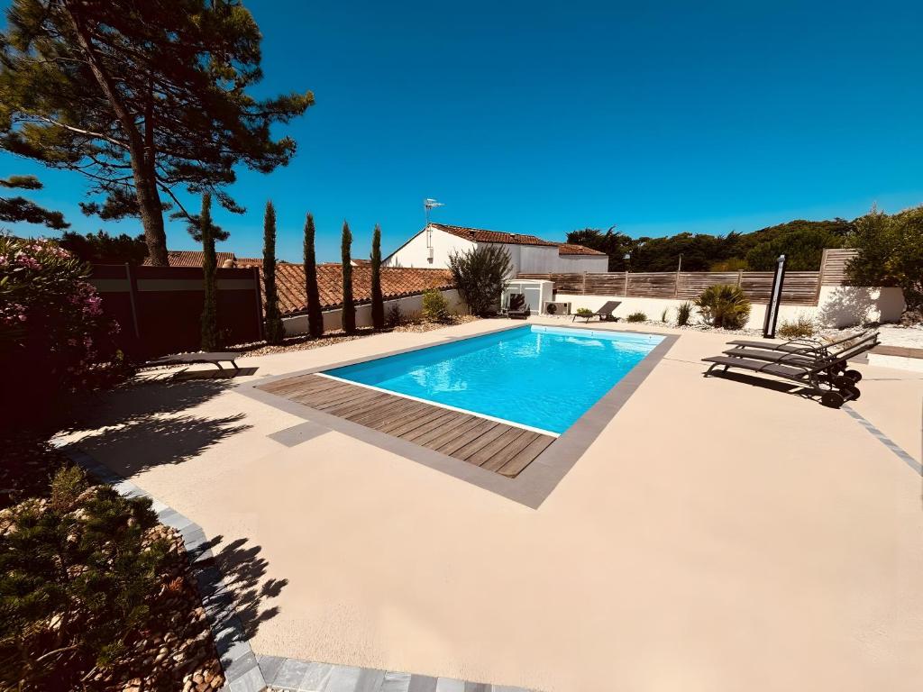 a swimming pool in a yard next to a house at Villa des sablons, piscine chauffée in La Tranche-sur-Mer