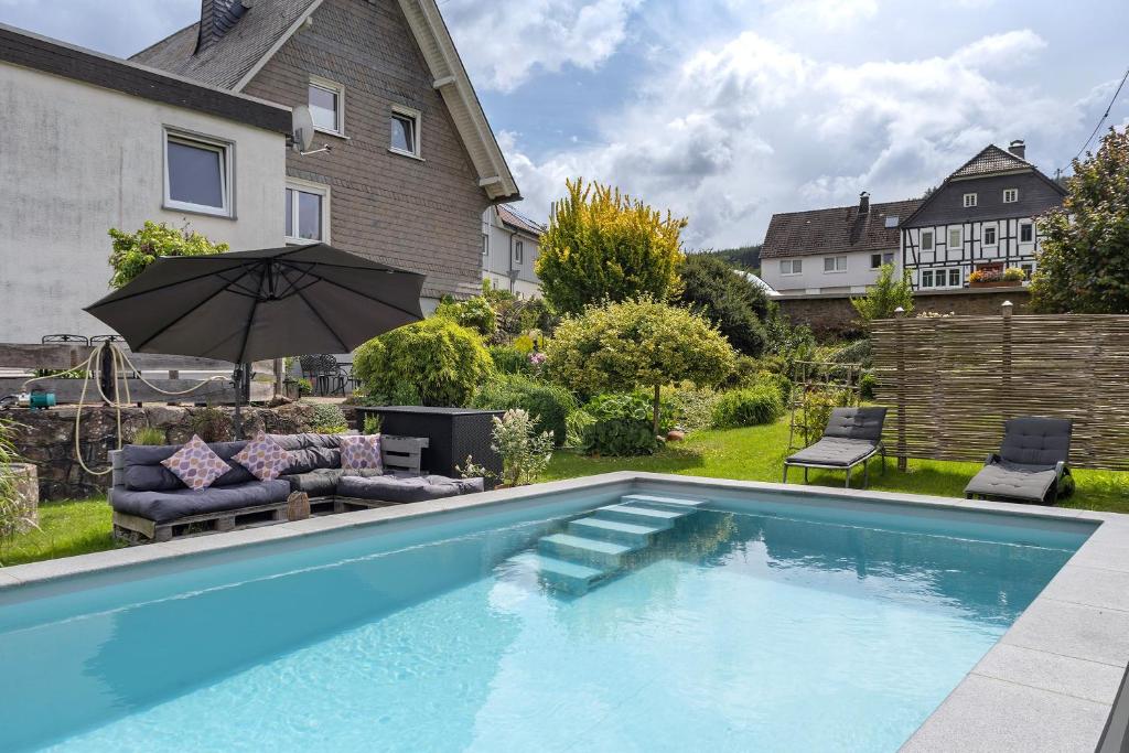 a swimming pool in a yard with an umbrella at Ferienwohnung Selbecke in Kirchhundem