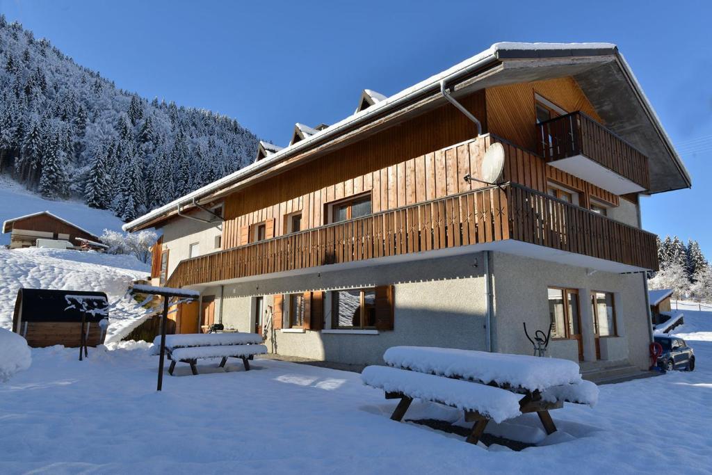 a building with benches in the snow in front of it at Coeur de Charmy Spa bien-être in Abondance