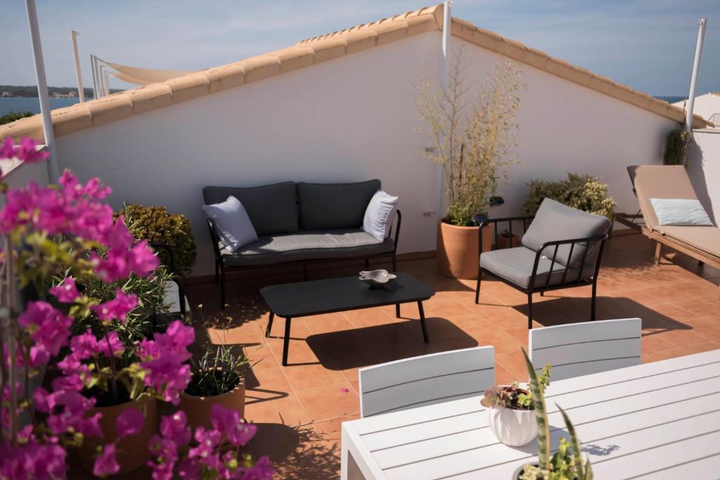a patio with a couch and chairs and flowers at Edificio can Sord Apto nº 2 in La Savina