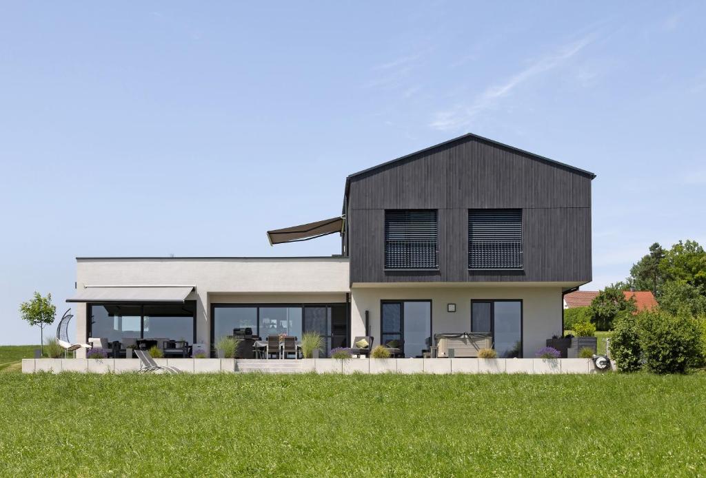 a house with a black roof on a green field at Chalet Am Ried in Bad Wurzach