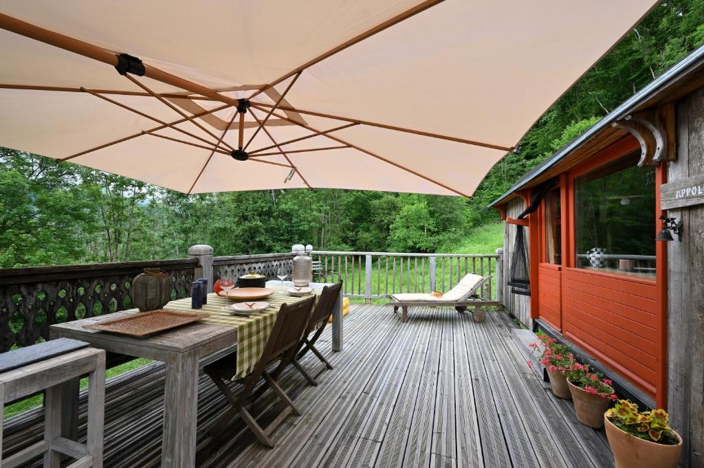 a patio with a table and an umbrella on a deck at Roulotte Appoline in Arrien-en-Bethmale