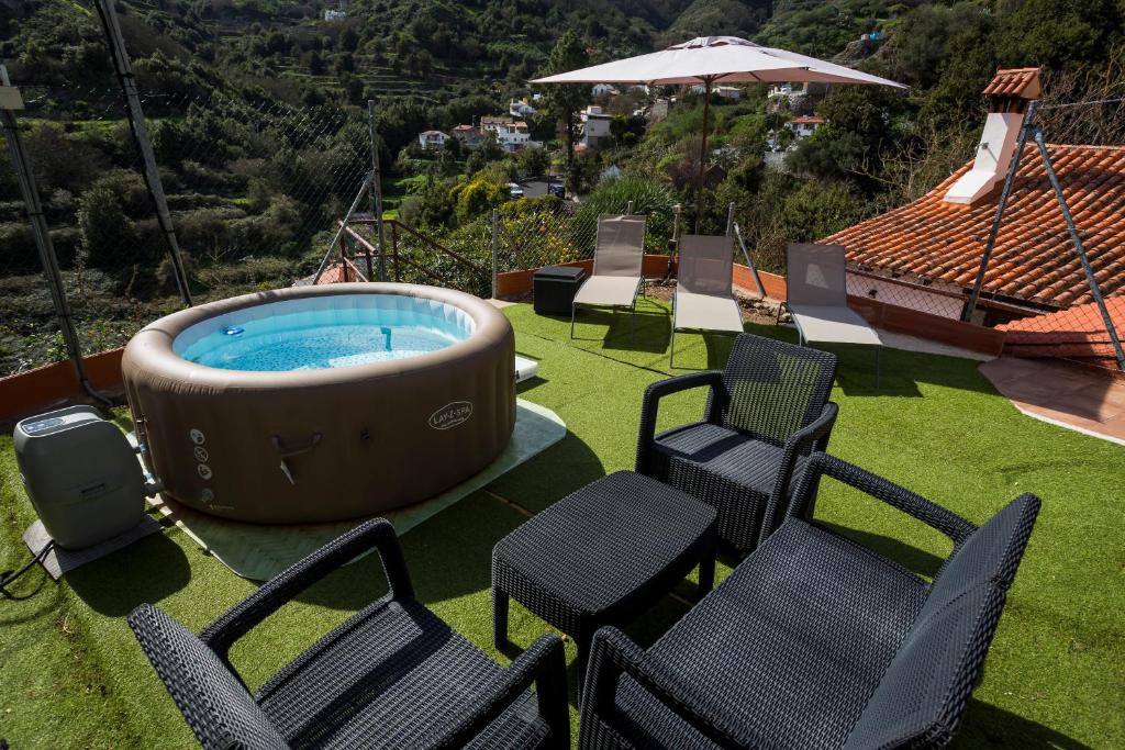 a group of chairs and a hot tub on a lawn at Casa Rural La Escalerilla in Teror