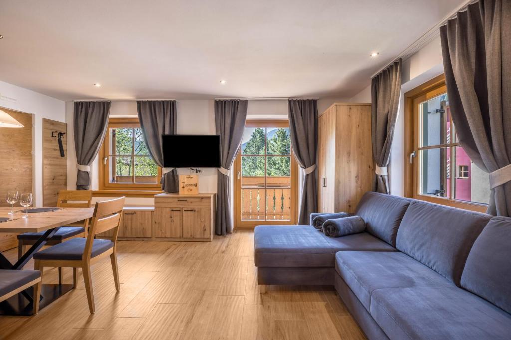 a living room with a blue couch and a table at Lechnerhof Fane Alm in Valles