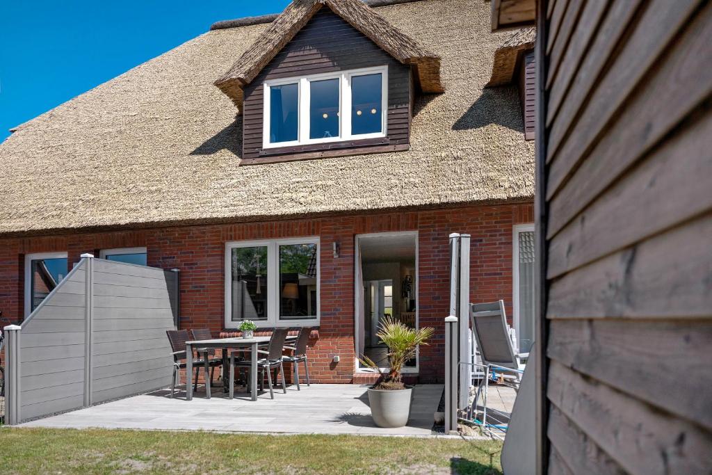 a brick house with a table and chairs on a patio at Ferienhaus Düün Drööm in Ording