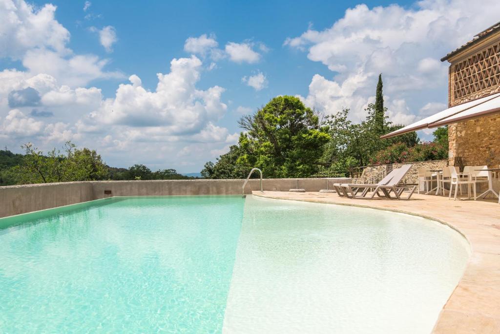 a swimming pool with two chairs and a table at Brotes Appartamento Castagno in Sovicille