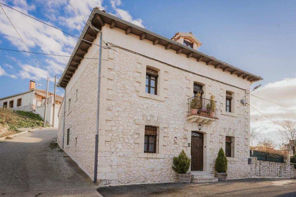 a white stone house with a balcony on a street at La Morada del Cura in Calabazas