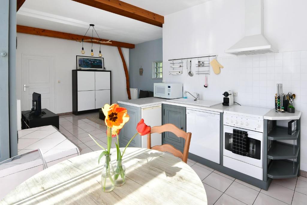 a kitchen with a table with a vase of flowers on it at Domaine De L'olympe in Domart-en-Ponthieu