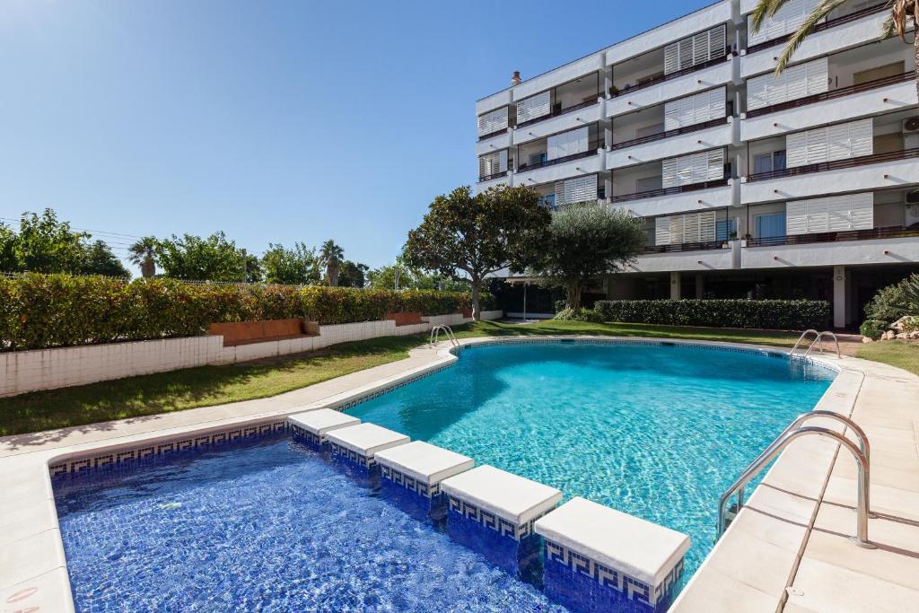 a swimming pool with lounge chairs next to a building at Canet Platja Apartment in Canet de Mar