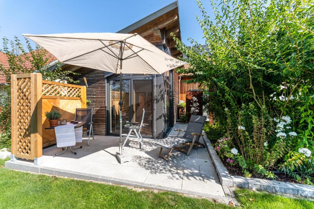 a patio with a table and chairs and an umbrella at Naturnahe Ferienwohnung Deuerling in Deuerling