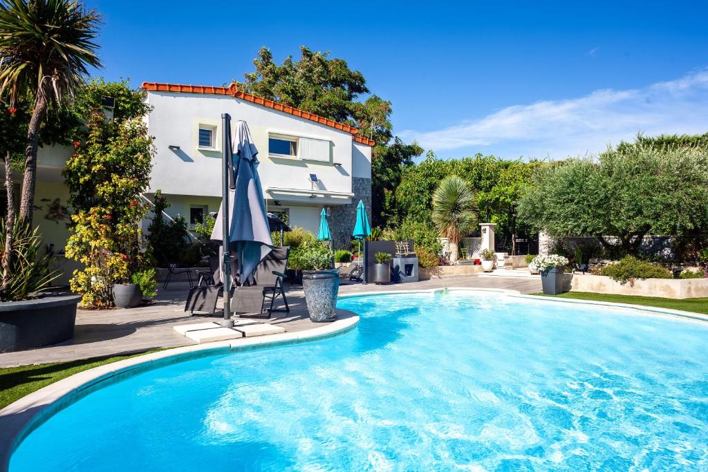 a swimming pool with an umbrella and a house at Lucerta Bella in Aix-en-Provence