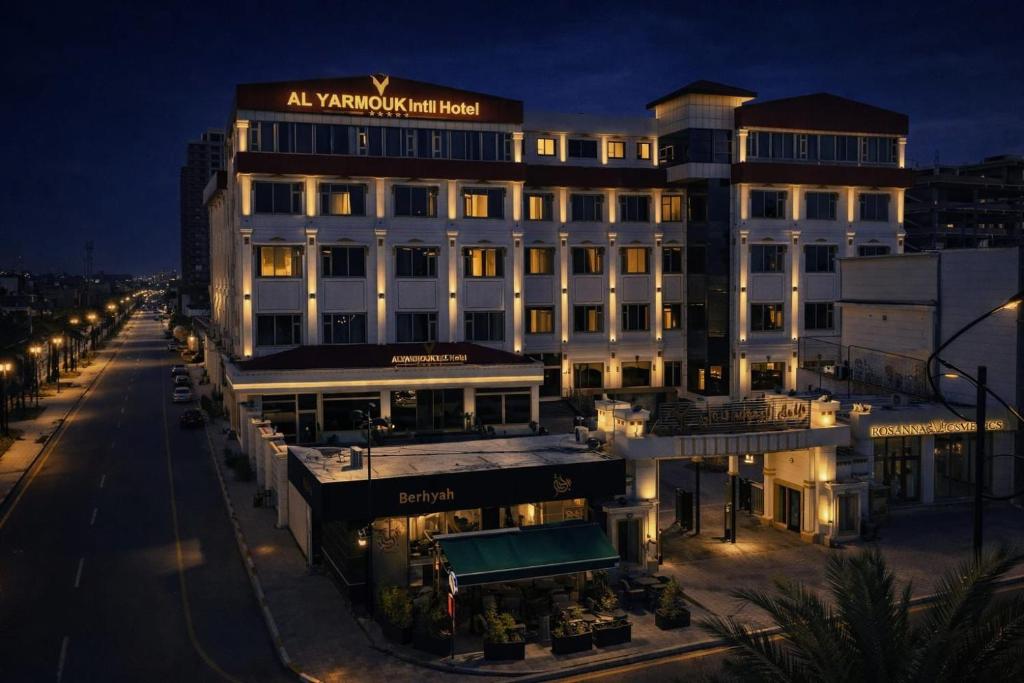 a large white building on a city street at night at Al Yarmouk International Hotel in Baghdād