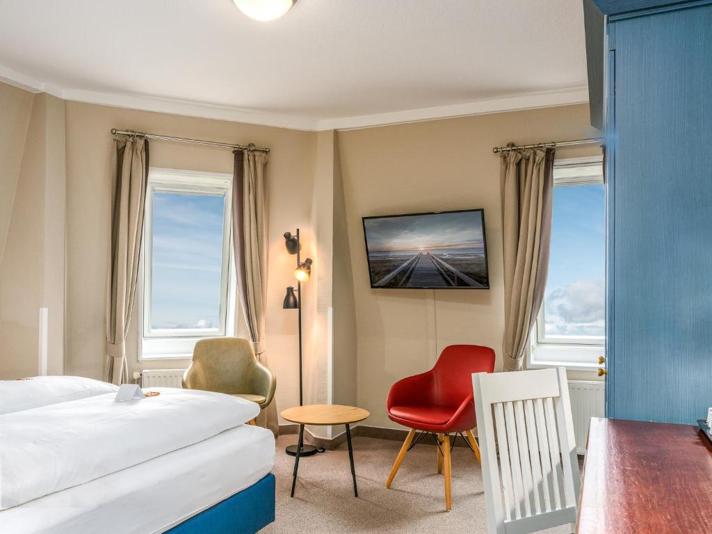 ein Hotelzimmer mit Bett, Tisch und Stühlen in der Unterkunft PLAZA Premium Sylt in Wenningstedt-Braderup