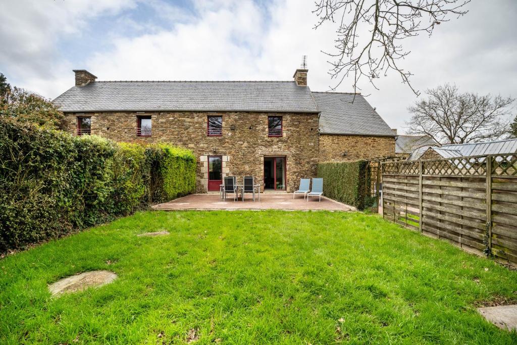 an old stone house with a fence and a yard at Gite Palombe in Lanvallay